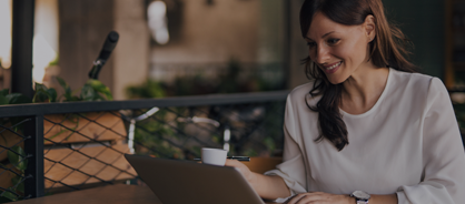 Smiling woman sitting at Cafe with laptop and coffee.